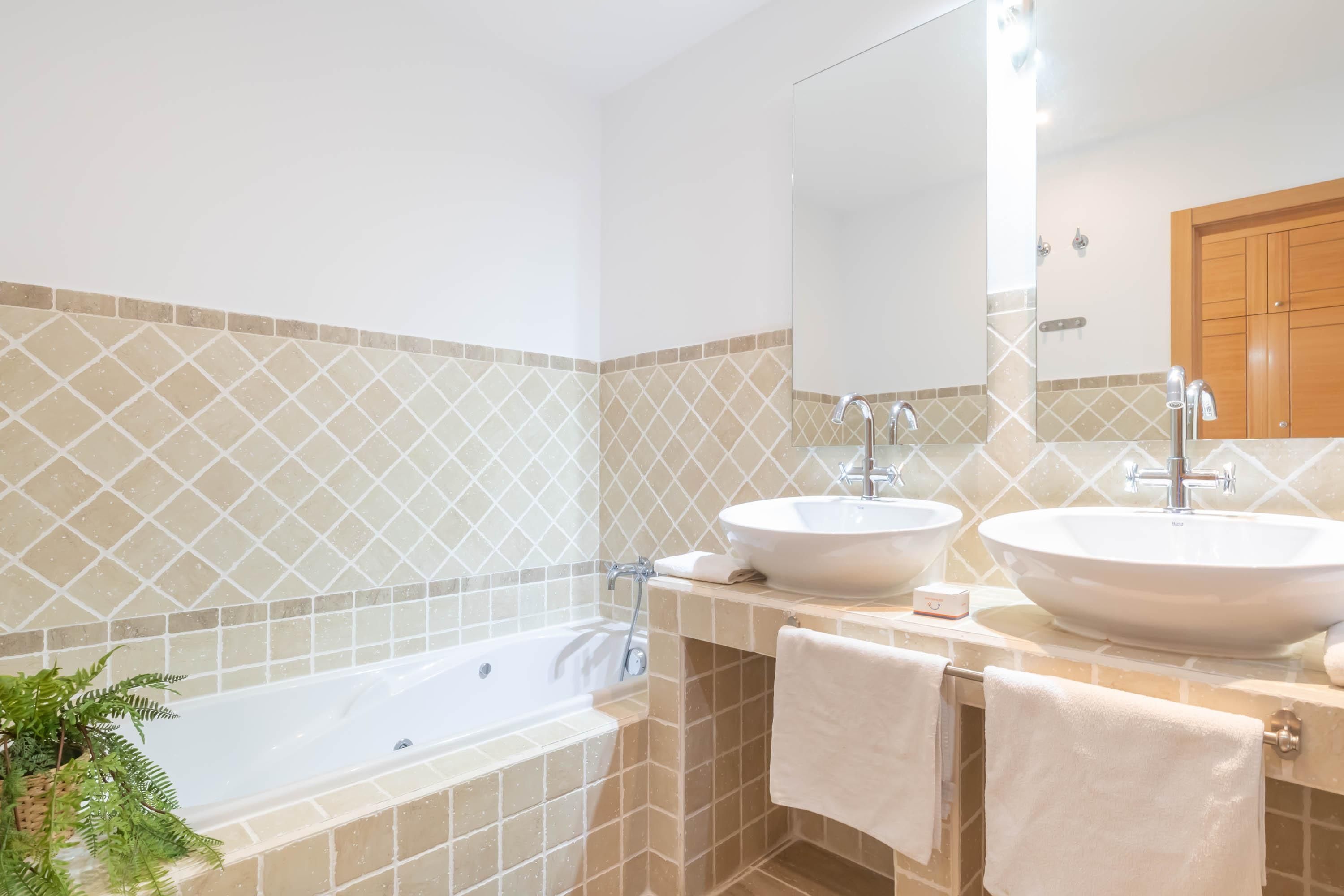A bathroom with two sinks, a large mirror, and a bathtub.