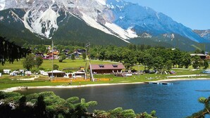 A lakeside resort with cabins, a swimming area, and a mountain backdrop. - Apartment in Vorberg Near Dachstein Glacier (Ramsau am Dachstein)