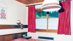 A bedroom with a bed, a window with curtains, a wall-mounted lamp, and a wall decoration. - Apartment in Vorberg Near Dachstein Glacier (Ramsau am Dachstein)