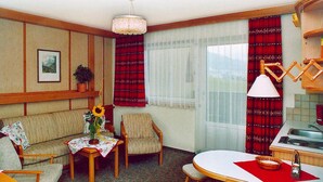 A compact living space with a sofa, armchair, dining table, and a kitchen area. - Apartment in Vorberg Near Dachstein Glacier (Ramsau am Dachstein)