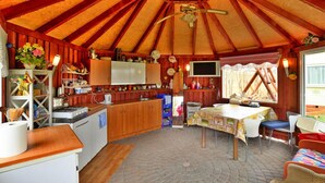 A cozy kitchen with wooden cabinets, a stove, and a dining area with a table and chairs. - Cottage by Lake Ostrowieckie With Private Beach (Malechowo)
