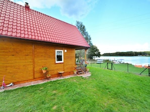 A wooden cabin with a red roof, a small porch, and a view of a lake. - Large Holiday Home With a Lake View (Malechowo)