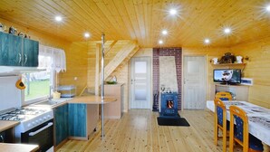 A wooden cabin interior with a kitchen, dining area, and fireplace. - Cottage by Lake Ostrowieckie With Private Beach (Malechowo)