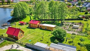 A residential area with a house, a red-roofed barn, and a garden. - Cottage by Lake Ostrowieckie With Private Beach (Malechowo)