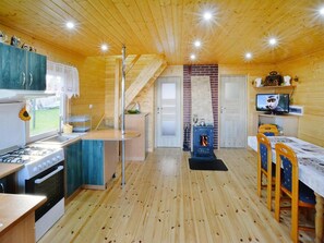 Ein Holzinnenraum mit Küche, Essbereich und Kamin.