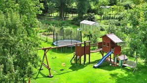 A playground with a swing set, slide, and climbing structure. - Cottage by Lake Ostrowieckie With Private Beach (Malechowo)
