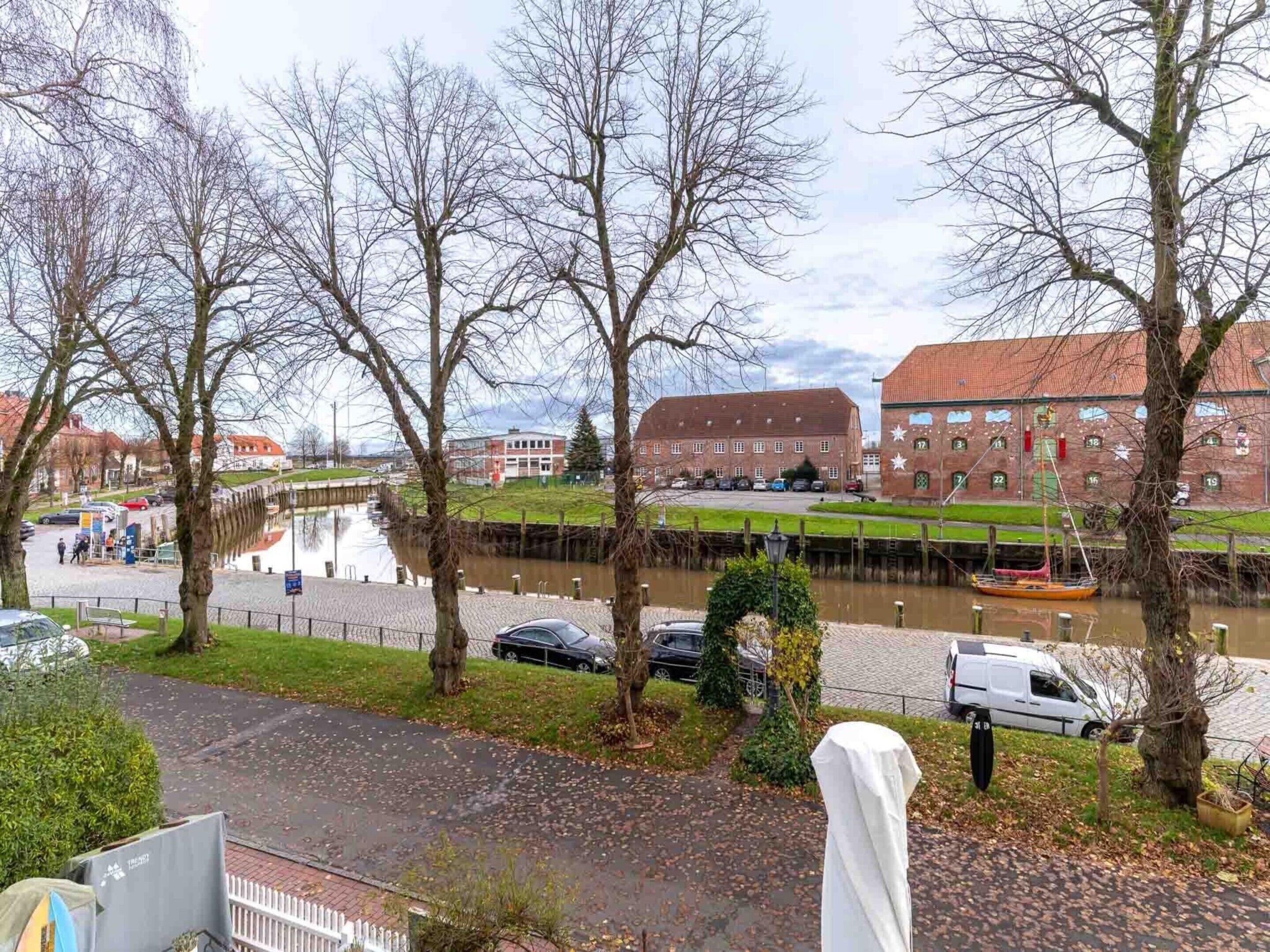 A riverside view with a canal, trees, and a building with numbered windows.