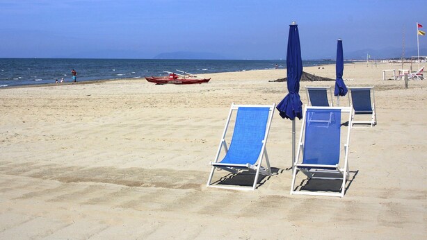 A beach with blue lounge chairs and umbrellas, a red boat, and a clear sky. - Holiday Home Fragola, Capezzano Pianore (Camaiore)