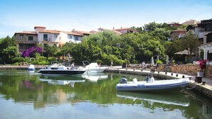 A marina with boats docked, surrounded by residential buildings and greenery. - Apartment in Sardinian Style With Pool (Olbia)