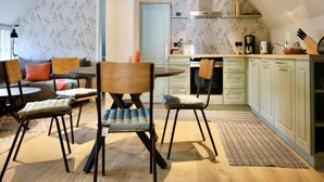 A modern kitchen with a dining area, featuring a round table, chairs, and a hanging light fixture. - Wohnung fur 4 Personen mit Garten in Nieblum (Nieblum)