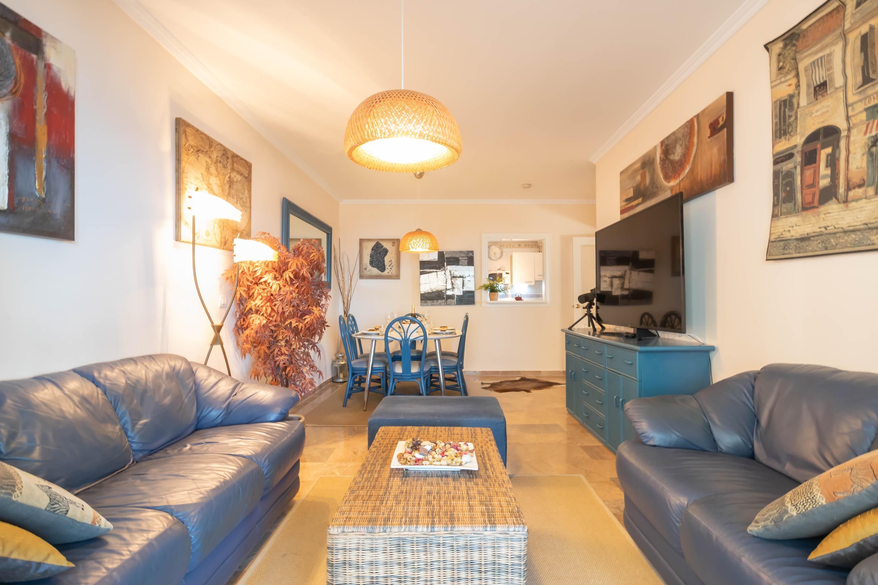 Un salon comprenant deux canapés en cuir, une table basse et un coin repas avec des chaises et une table.