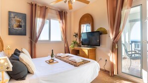 Ein Hotelzimmer mit Bett, Fernseher, Deckenventilator und Blick ins Freie.
