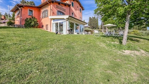 A large, two-story house with a sloped roof, a covered patio area, and a lawn. - Casa Paradiso With Wonderful Panorama (Capannori)