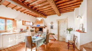A rustic kitchen with wooden beams, a dining table set for four, and a fireplace. - Casa Paradiso With Wonderful Panorama (Capannori)