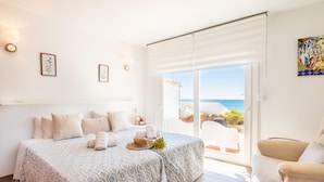 A bedroom with two beds, a balcony with a view of the sea, and a painting on the wall. - Bahia Dorada Complete Villa (Estepona)