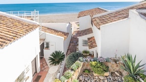 A coastal building with terracotta roofs, a narrow courtyard with potted plants, and a view of the sea. - Bahia Dorada Complete Villa (Estepona)