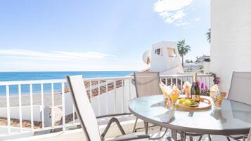 Enjoy a romantic sea view from this balcony, featuring a stylish table setting and comfortable seating.