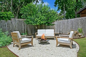 Relax by the fire pit surrounded by comfortable lounge chairs in a serene outdoor setting.