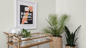 A framed poster with the text "DRINK LOCAL" and a decorative tray with glasses and a disco ball. - Austin Oasis – Zilker, Downtown, Pool, 3 Bedroom (Austin)