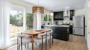 A modern kitchen with a central island, dark cabinetry, and a large refrigerator. - Austin Oasis – Zilker, Downtown, Pool, 3 Bedroom (Austin)
