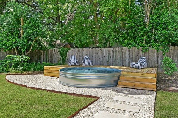 Relax in a hot tub surrounded by a serene garden and comfortable seating.