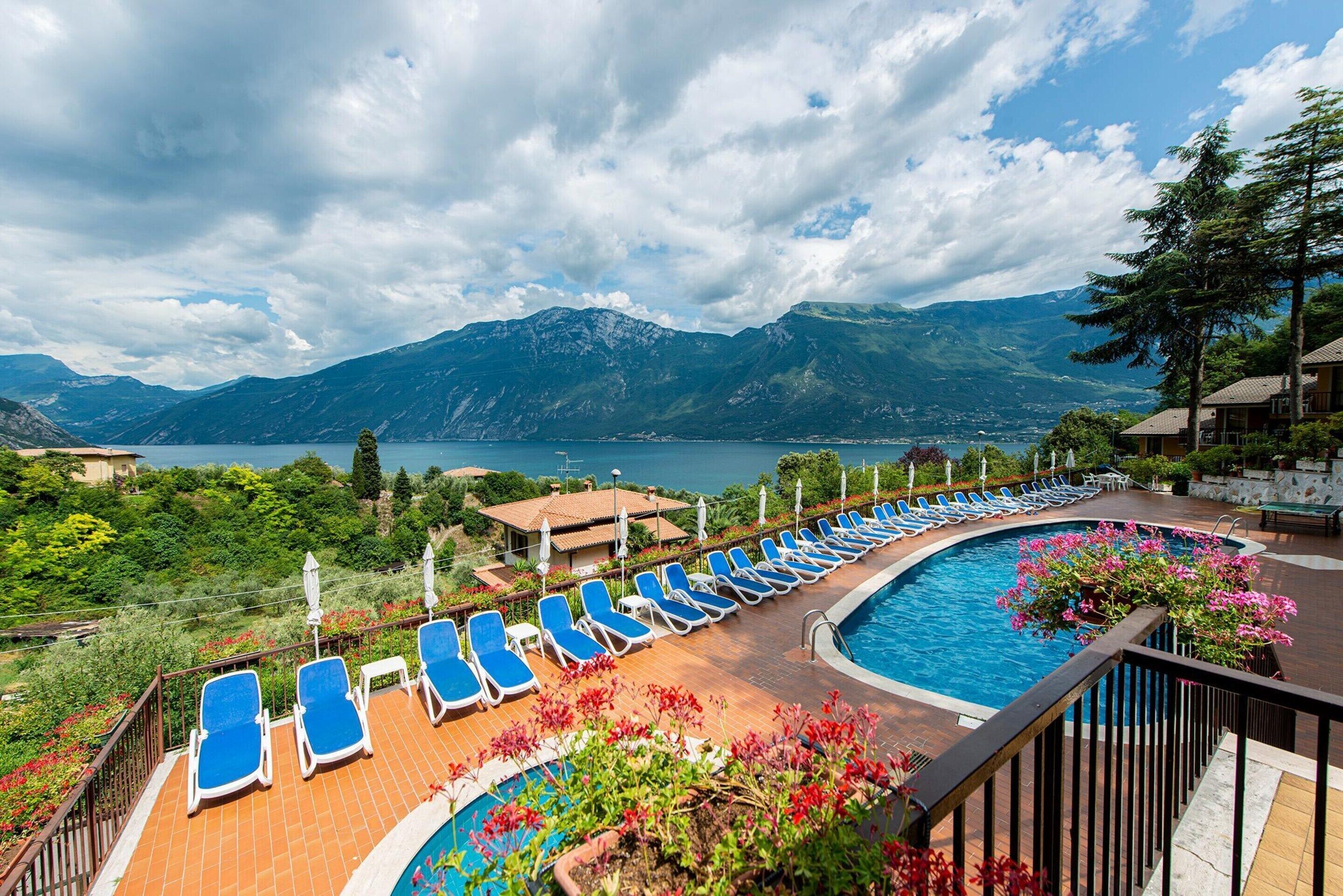 A poolside area with lounge chairs, a swimming pool, and a mountainous landscape in the background.