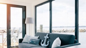 A modern living room with a grey sofa, a lamp, and a decorative anchor pillow. - Houseboat in Egernsund at the Marina Minde (Broager)