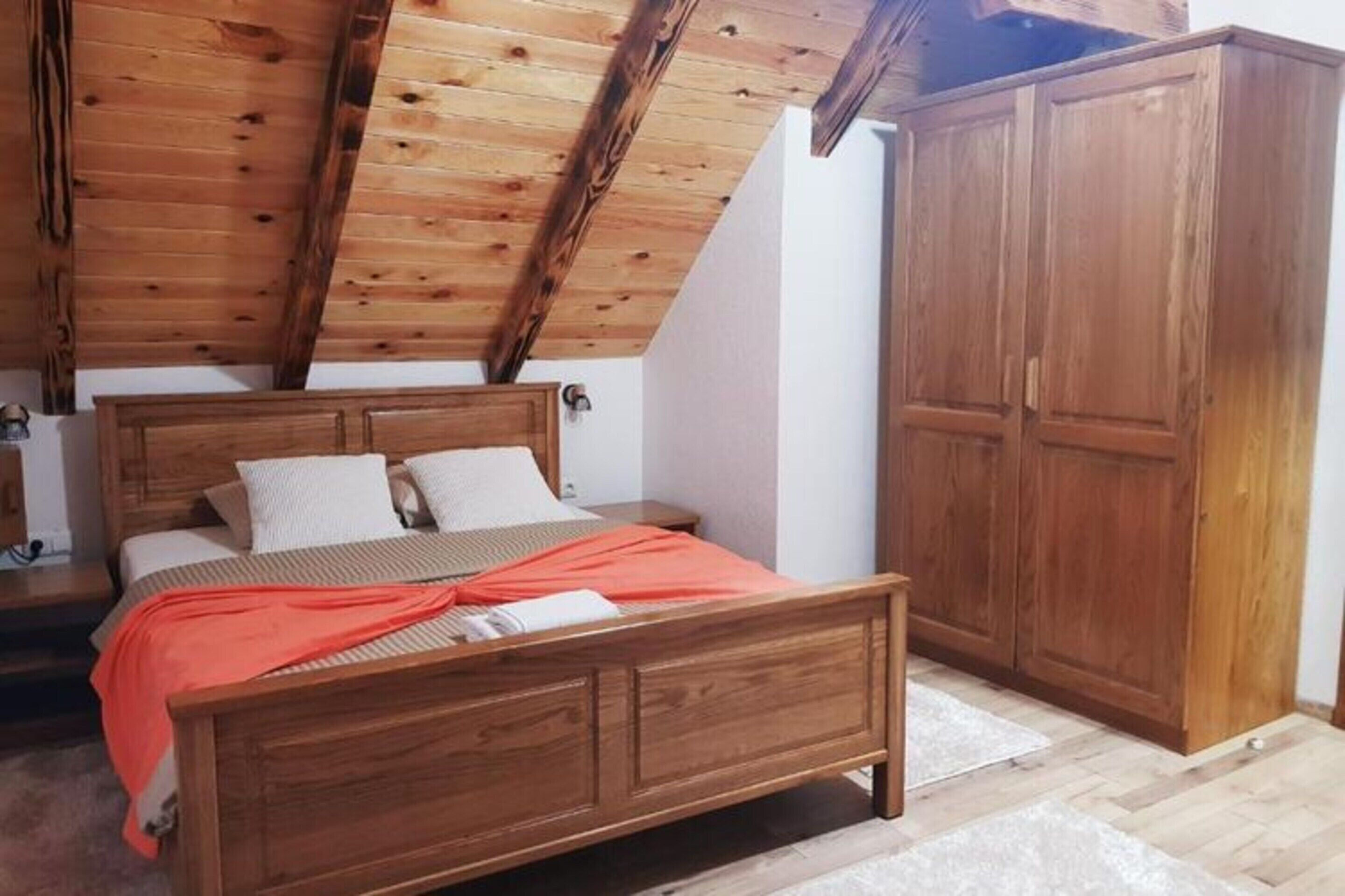A bedroom with a wooden bed, a wardrobe, and a sloped ceiling.