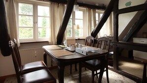 Un comedor con una mesa y sillas de madera, una ventana con cortinas y una lámpara.