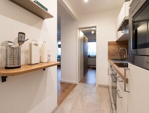 A modern kitchen with a wooden countertop, stainless steel appliances, and a view into the adjacent room. - Ferienwohnung mit Balkon in Westerdeichstrich (Westerdeichstrich)