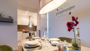 A dining area with a white table set for four, a bottle of water, and a decorative orchid. - Ferienwohnung mit Balkon in Westerdeichstrich (Westerdeichstrich)