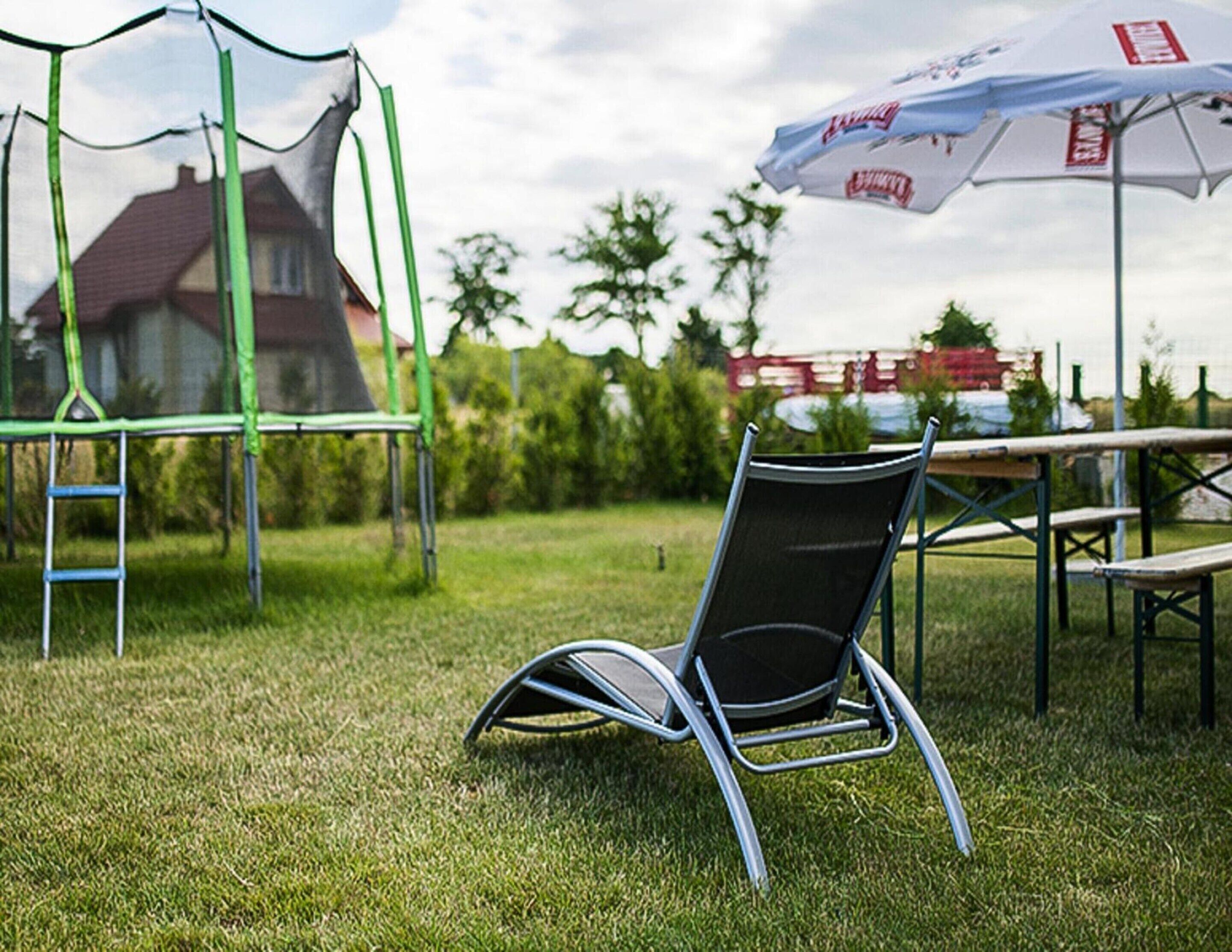 A chair in a grassy outdoor area with a netted play structure in the background.