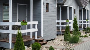 Hytter i række med hvide gelændere og grønne plantekasser på verandaen.