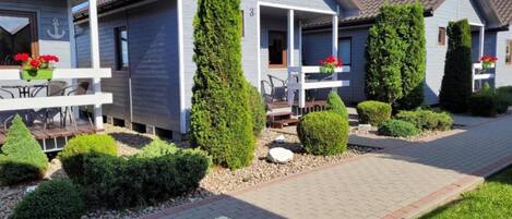 A row of blue cottages with white railings, each with a porch and potted plants.