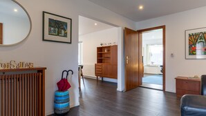 A spacious room with a wooden floor, a wooden cabinet with a mirror, and a door leading to another room. - Comfortable Holiday Apartment in St. Peter Ording (St. Peter-Ording)