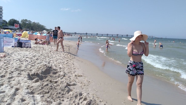 A beach with people, umbrellas, and a pier in the background. - Holiday House Near Emerald Lake Wapnica (Międzyzdroje)
