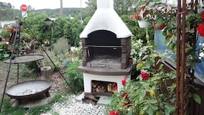 A traditional stone oven with a chimney, surrounded by a garden with various plants and flowers. - Holiday House Near Emerald Lake Wapnica (Międzyzdroje)