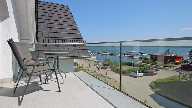 A balcony with a glass railing overlooking a marina with boats and a clear view of the water. - Reihenhaus in Plau am See mit Terrasse und Balkon (Plau am See)