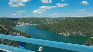 A scenic view of a river with a boat, surrounded by lush greenery and hills. - Biograd Beachside Family Apartment (Biograd na Moru)