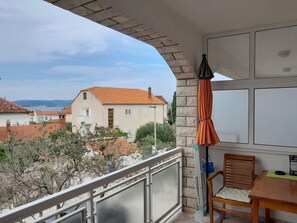 Enjoy the view from this balcony with a window overlooking houses and trees.