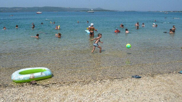 A beach with people swimming and playing, a clear sky, and boats in the distance. - Biograd Beachside Family Apartment (Biograd na Moru)