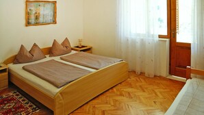 A bedroom with a wooden bed, a nightstand, a painting on the wall, and a window with curtains. - Biograd Beachside Family Apartment (Biograd na Moru)