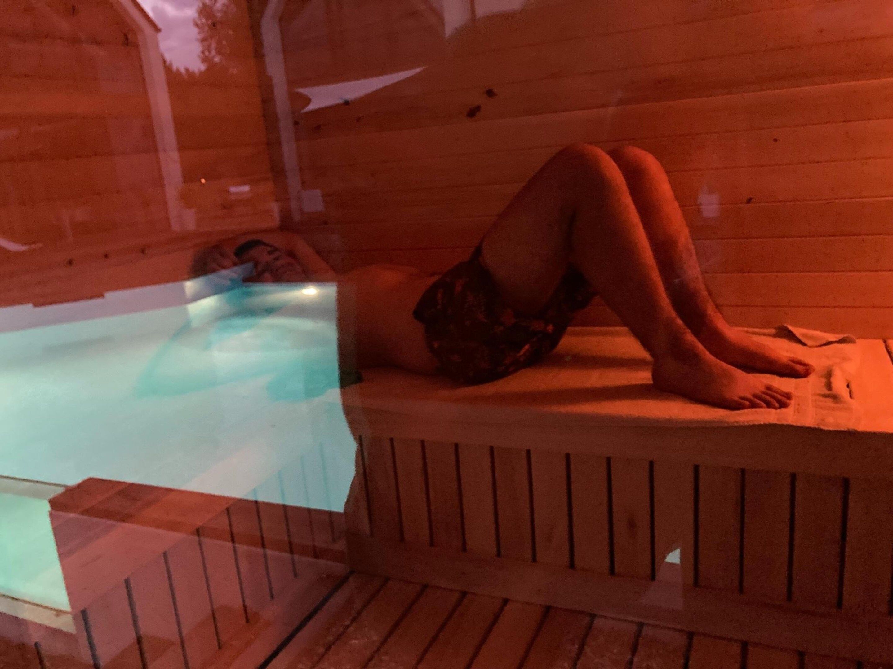 Eine Person liegt auf einer Holzbank am Pool.