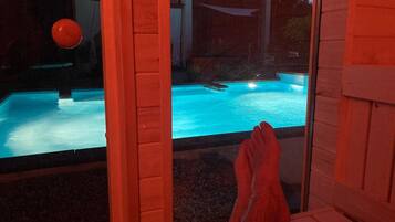 A pool with a wooden deck and a red structure in the foreground.