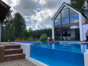 A modern house with a swimming pool, wooden steps, and a garden.