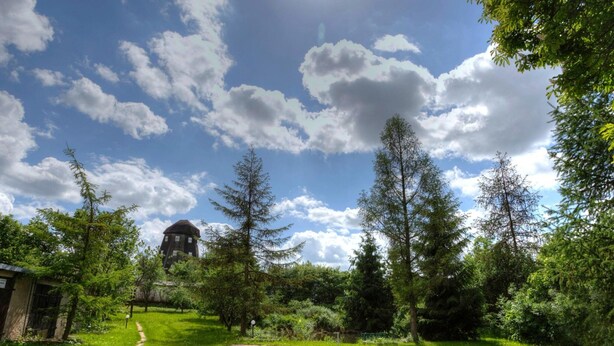 A grassy area with a water tower and trees. - Apartment in Masuria With Private Pond (Gizycko)