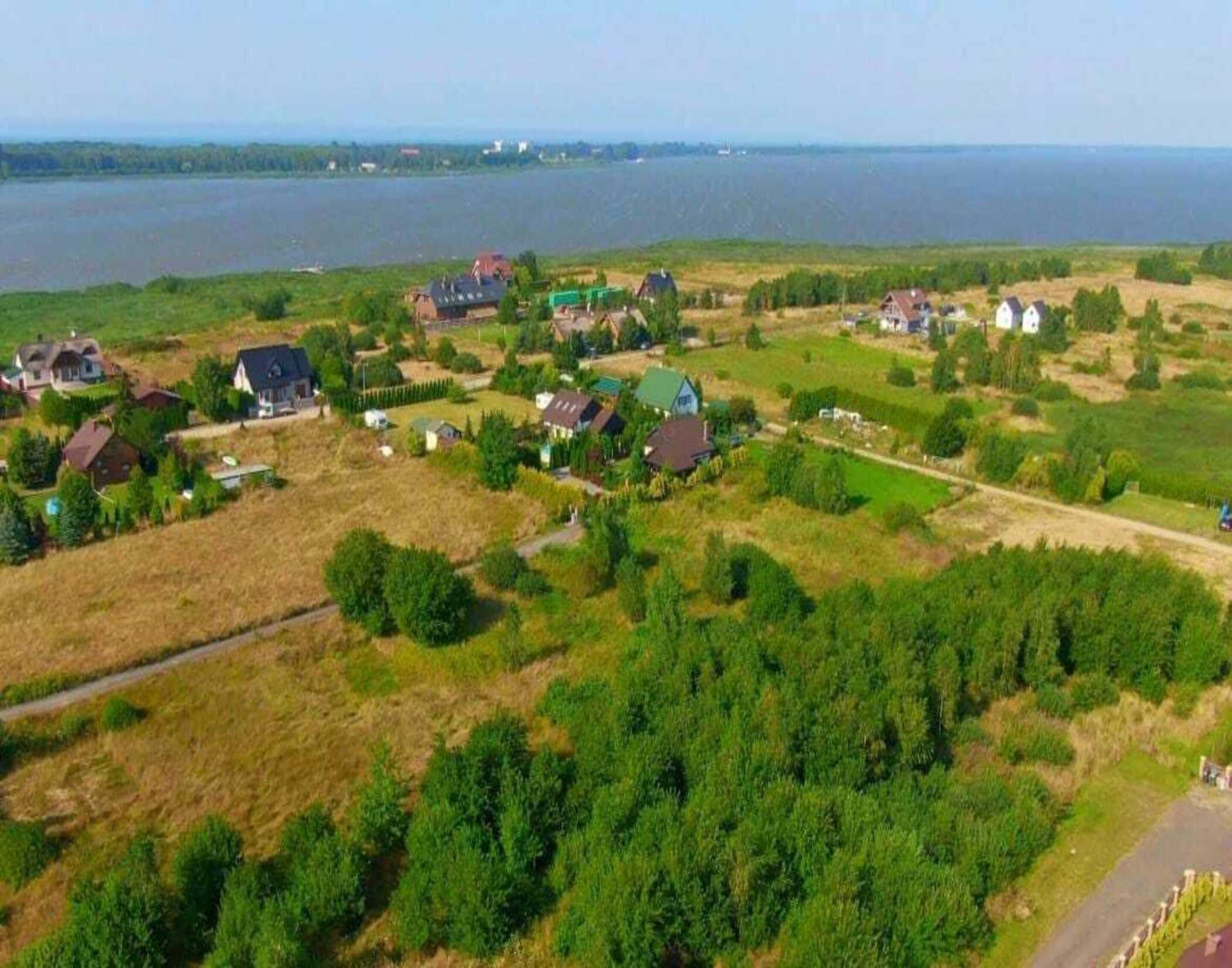 Vue aérienne d’un quartier résidentiel avec des maisons, une route et une étendue d’eau en arrière-plan.