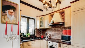 A kitchen with white cabinets, a brick backsplash, a stove, and a chandelier. - Large Holiday Home by the Lake, Close to the sea (gmina Będzino)