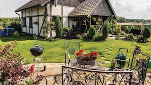 A two-story house with a sloped roof, a well-maintained lawn, and a patio area with a table and chairs. - Large Holiday Home by the Lake, Close to the sea (gmina Będzino)