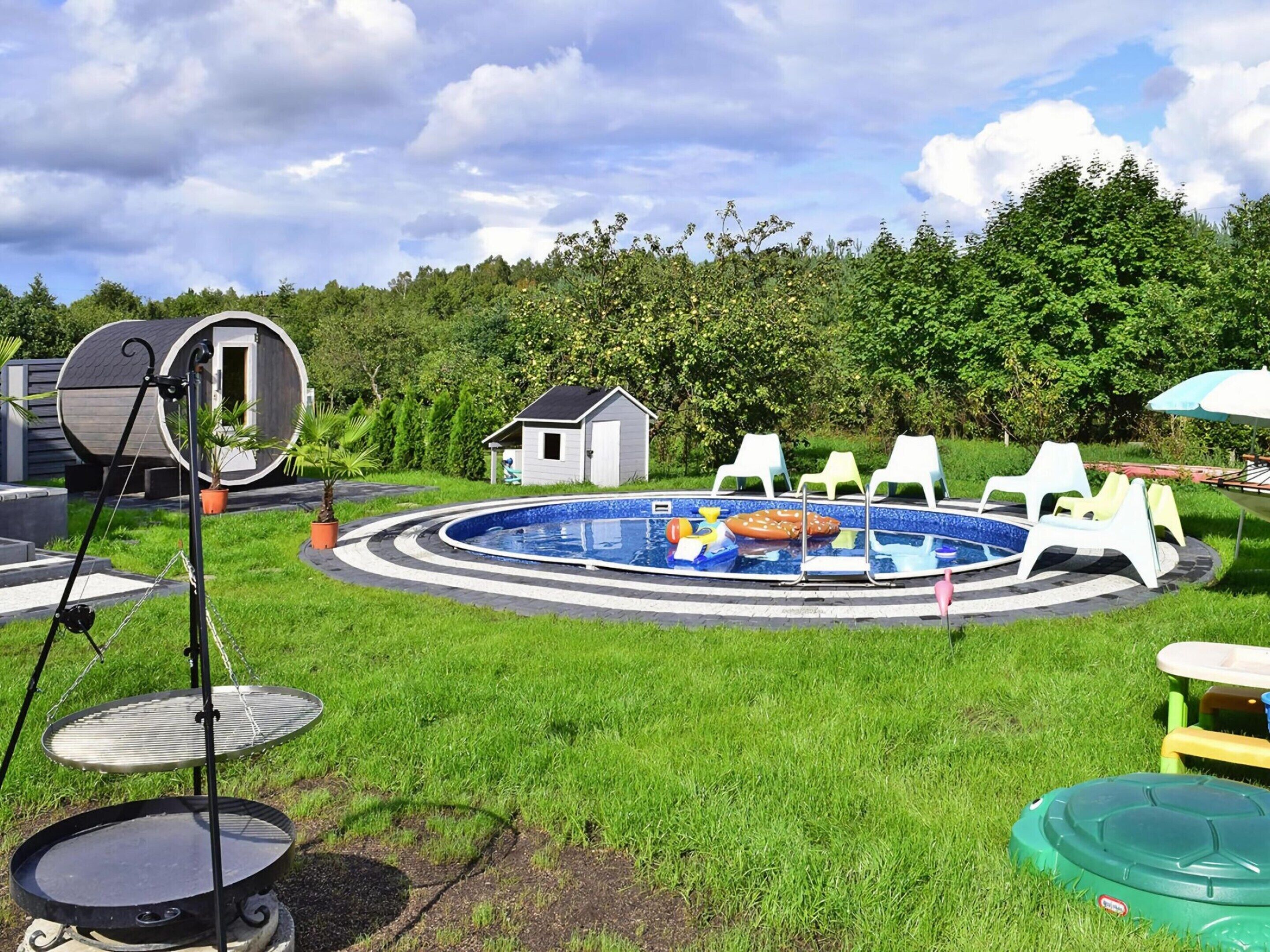 A circular swimming pool with lounge chairs and a small shed in a grassy area.